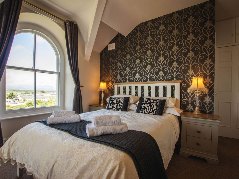 A bedroom with a bed and window at Noddfa Country House in Harlech