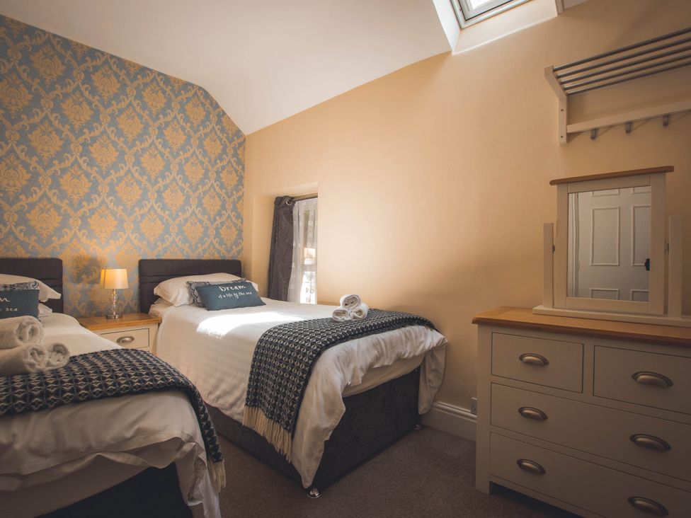 A bedroom with two beds and a dressing table at Noddfa Country House in Harlech
