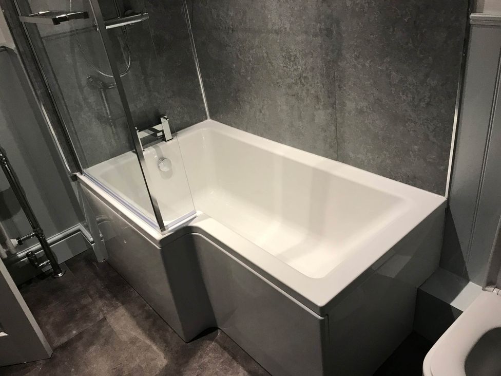 A bathroom with a bathtub and a shower screen at Noddfa Country House in Harlech