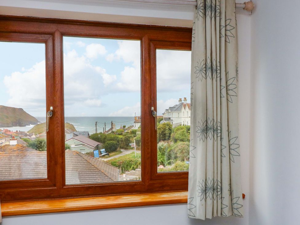 A view of the sea and houses through a window at Surf View in Hope Cove
