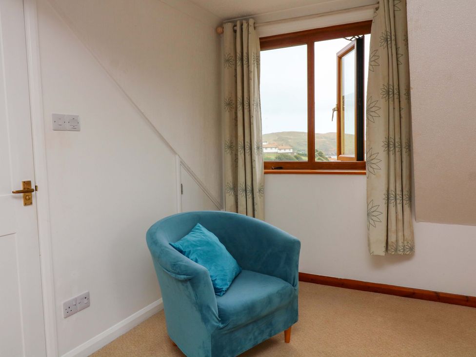 A seating area with a chair and window at Surf View in Hope Cove