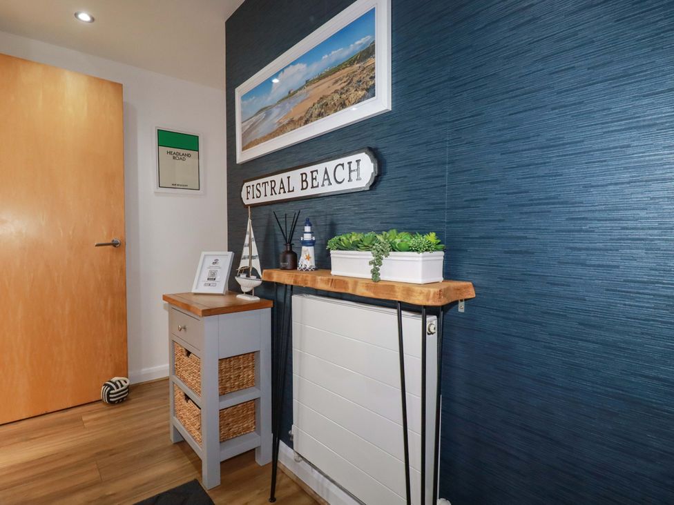 A hallway with a wooden shelf and sign at Penthouse @46Zinc - Headland View, Newquay