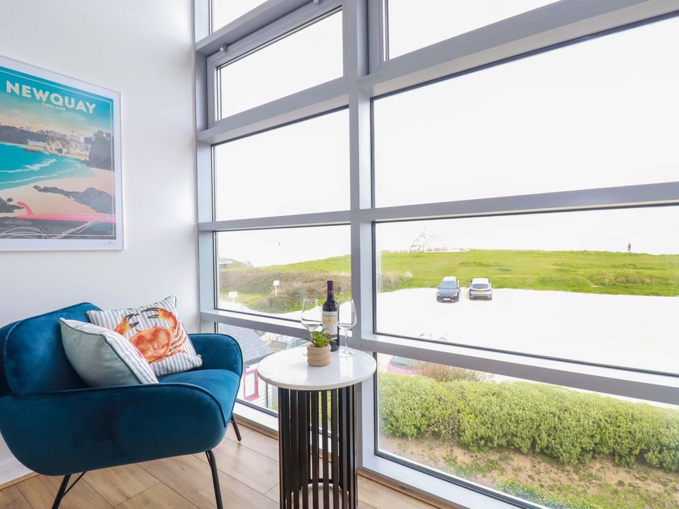 A living room with a chair and table by a large window at Penthouse @46Zinc - Headland View in Newquay