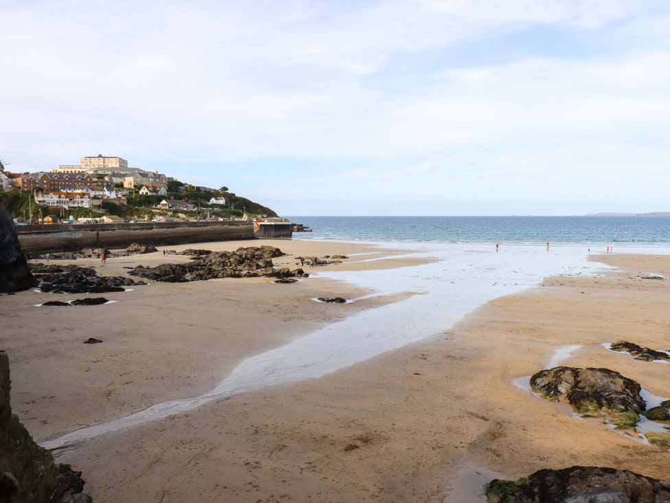 A beach with rocky formations and buildings in the background at Penthouse @46Zinc - Headland View, Newquay
