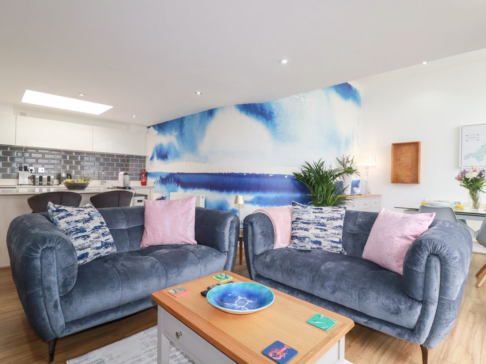 A living room with sofas and a kitchen area at Penthouse @46Zinc - Headland View Newquay