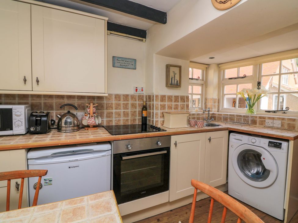 A kitchen with cabinets, appliances, and a work surface at 1 The Square Hope Cove
