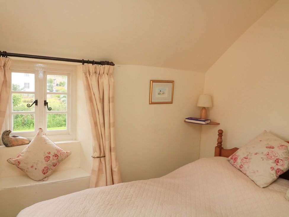A bedroom with a window, bed, and lamp at 1 The Square in Hope Cove
