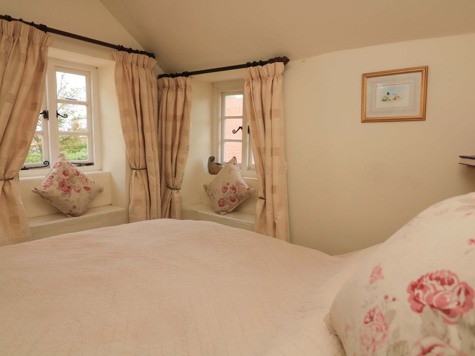 A bedroom with a bed and windows at 1 The Square in Hope Cove