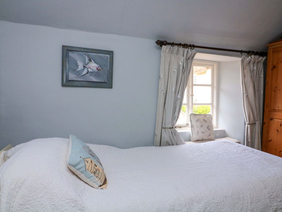 A bedroom with a bed, window, and wardrobe at 1 The Square, Hope Cove