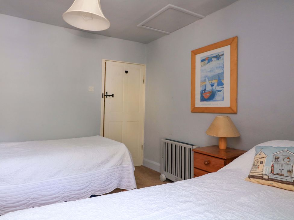 A bedroom with twin beds and a bedside table at 1 The Square Hope Cove
