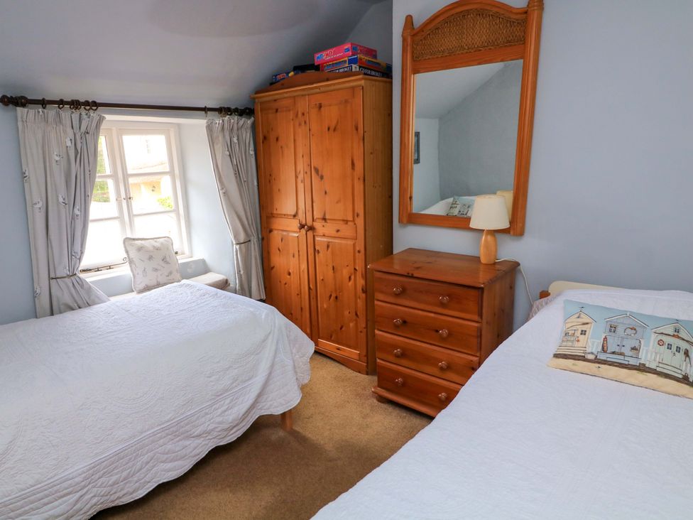 A bedroom with two beds and a wardrobe at 1 The Square in Hope Cove