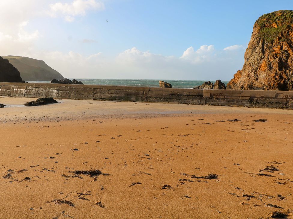 A beach scene with sand and rocks at 1 The Square Hope Cove