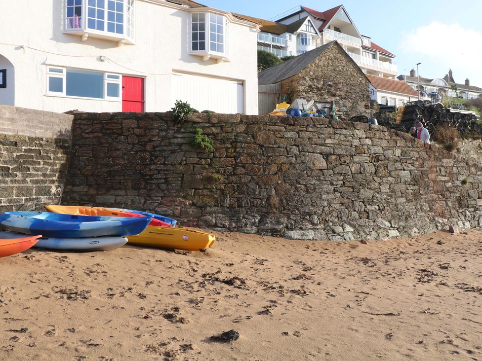 A beach scene with kayaks on sand near a rock wall at 1 The Square Hope Cove
