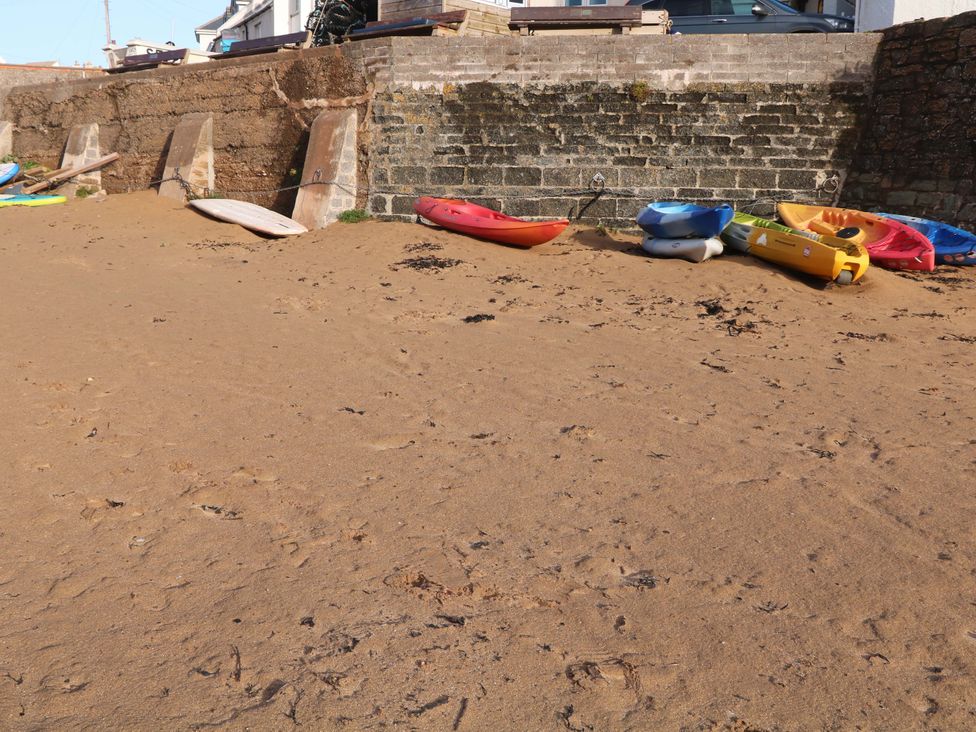An outdoor area with kayaks and surfboards on the sand at 1 The Square Hope Cove