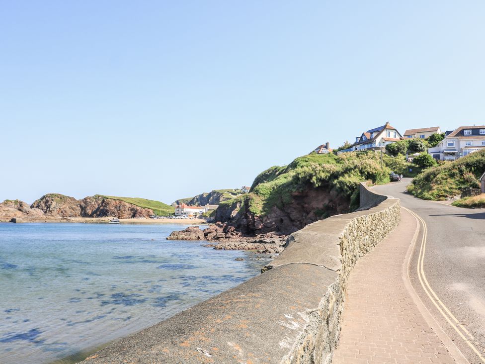 A coastal view with a road and houses at 1 The Square in Hope Cove