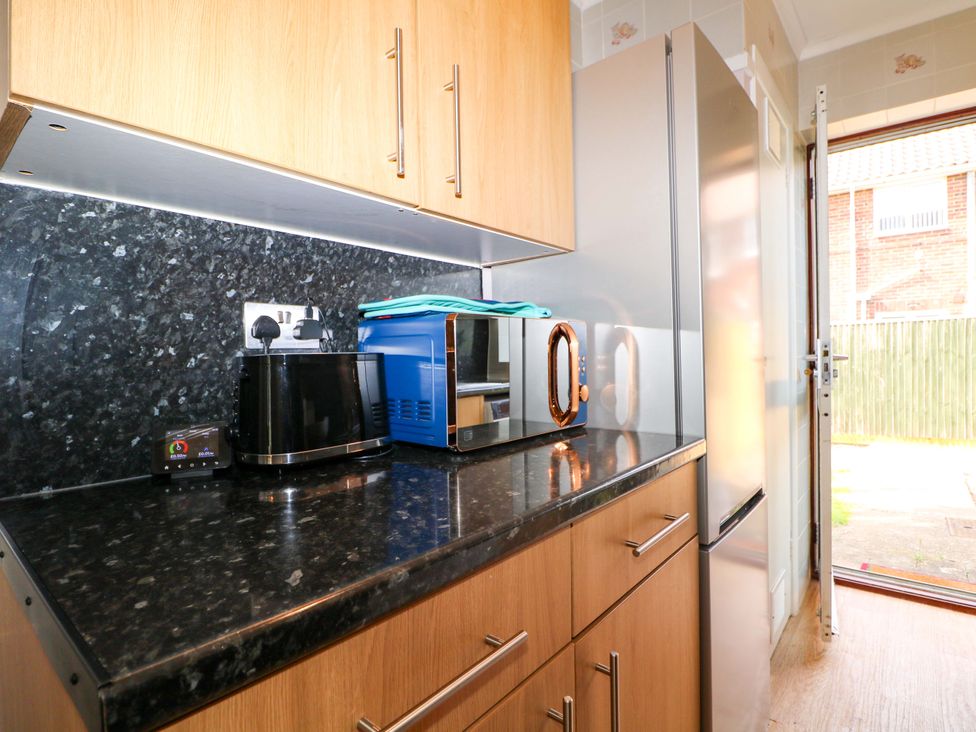 A kitchen with appliances including a microwave and fridge at 6 Ashton Gardens Rustington