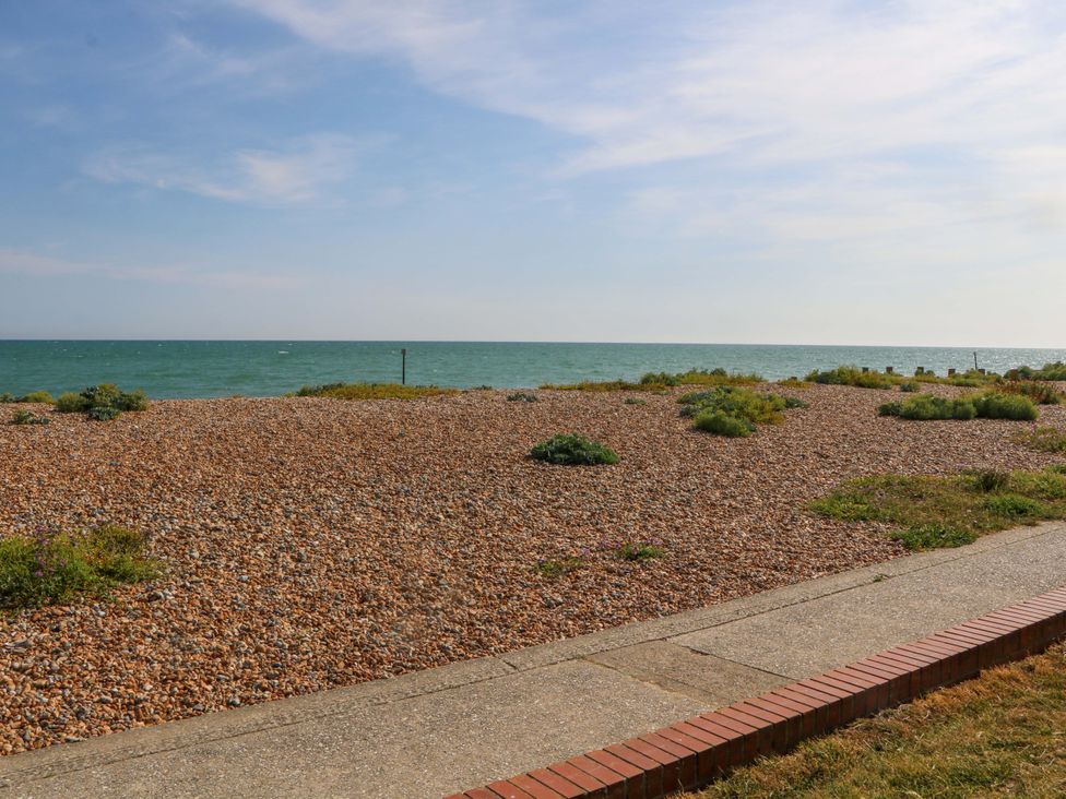A seaside view with pebbles and vegetation at 6 Ashton Gardens in Rustington