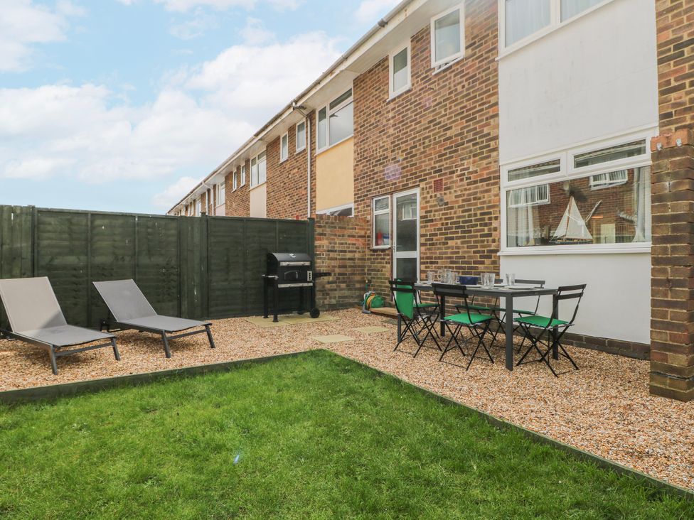 A garden with loungers and a table set at Pebble Place in Rustington