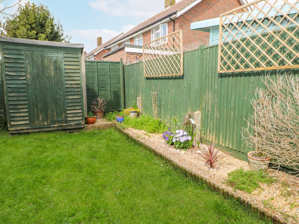 A garden with a shed, fence, and various plants at Pebble Place in Rustington