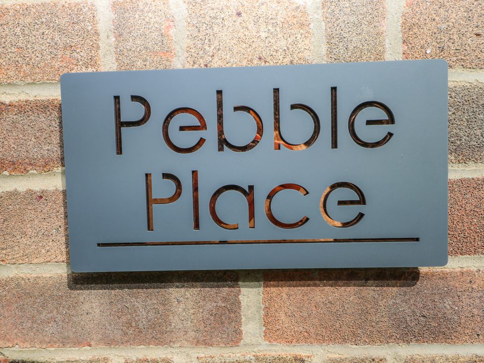 A sign with the name Pebble Place on a brick wall