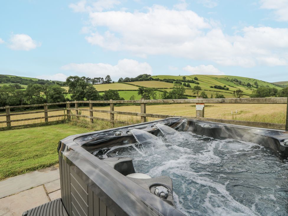 A hot tub with a view of hills and a fence at Waun Yscir Merthyr Cynog near Brecon