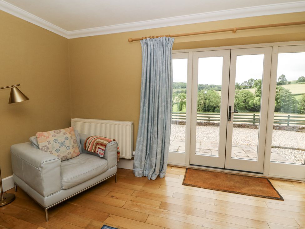 A living room with a sliding door and an armchair at Waun Yscir in Merthyr Cynog near Brecon