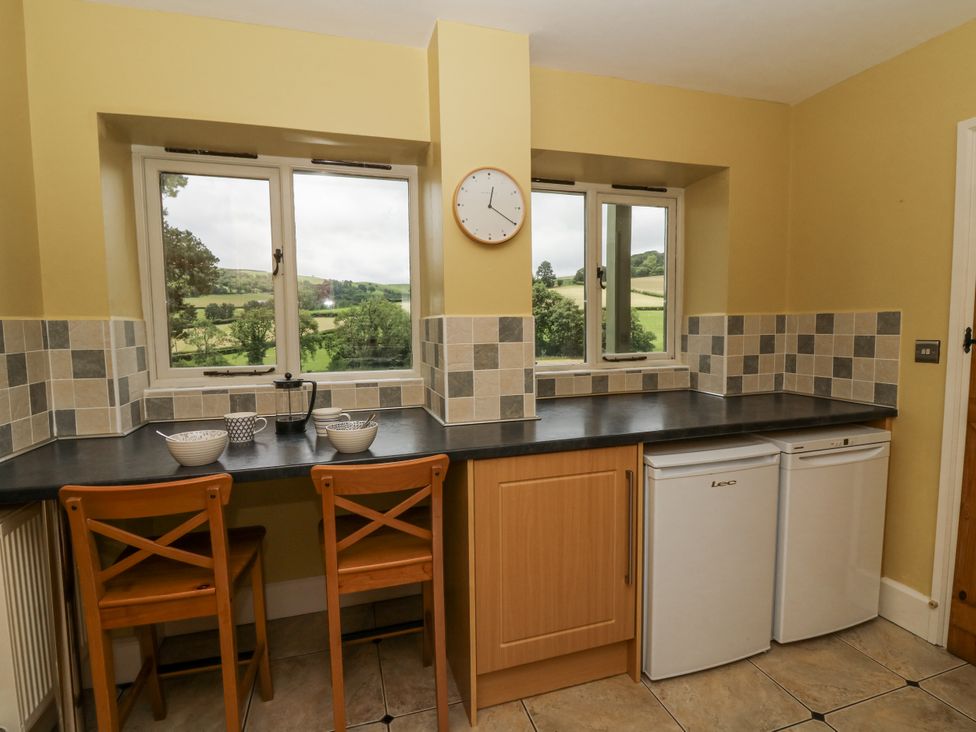 A kitchen with counter, fridge, and windows at Waun Yscir in Merthyr Cynog near Brecon