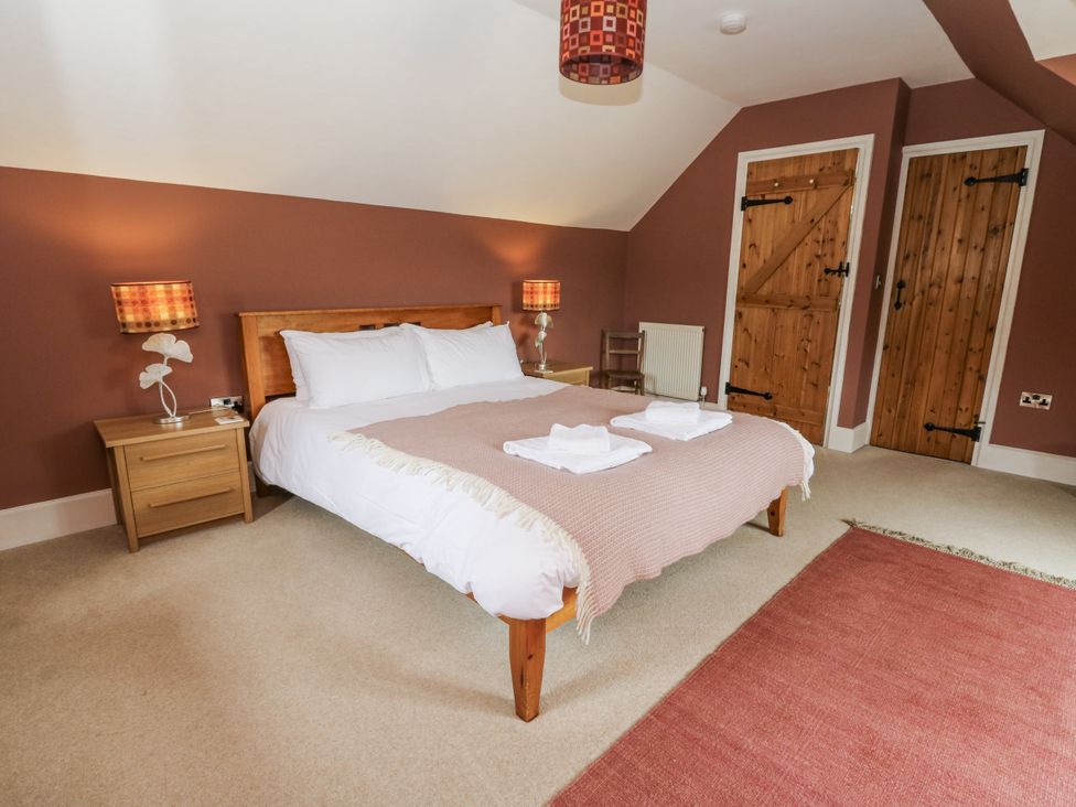 A bedroom with a bed, bedside lamps, and wooden doors at Waun Yscir Merthyr Cynog near Brecon