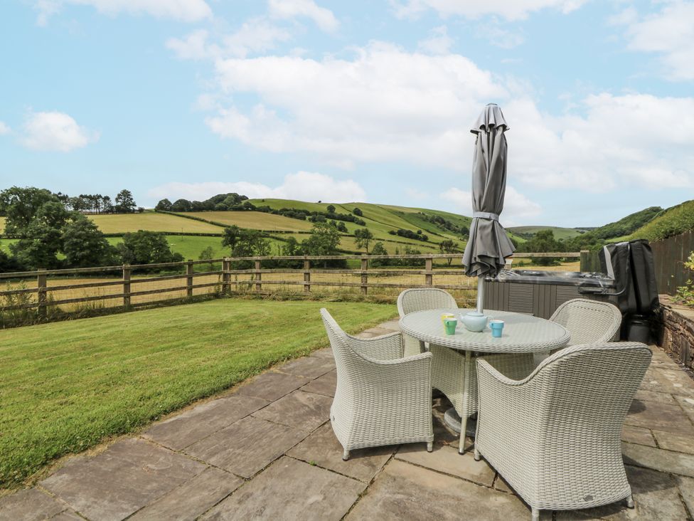 An outdoor area with a table and chairs and a hot tub at Waun Yscir Merthyr Cynog near Brecon