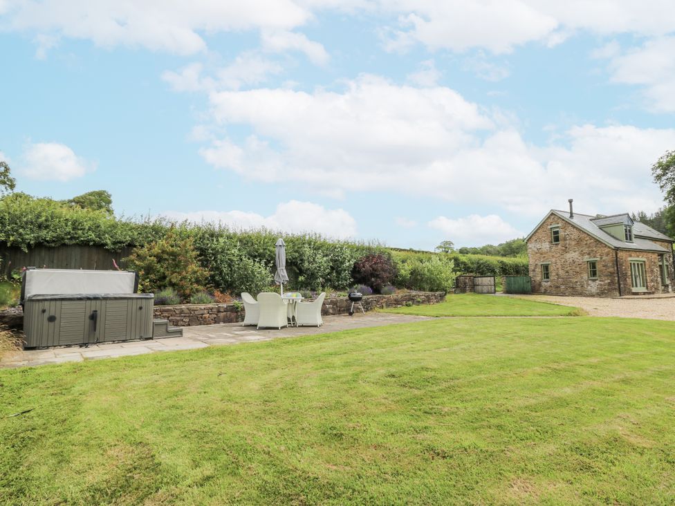 A garden with a hot tub and dining area at Waun Yscir Merthyr Cynog near Brecon