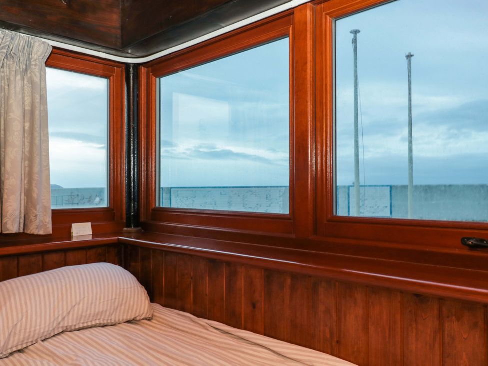 A bedroom with a bed and windows at Sammy Hakes Cottage