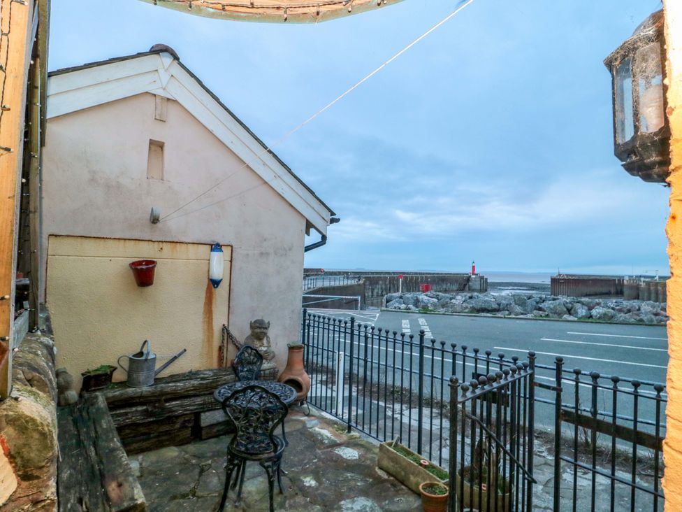 An outdoor area with a bench and chairs by a road at Sammy Hakes Cottage