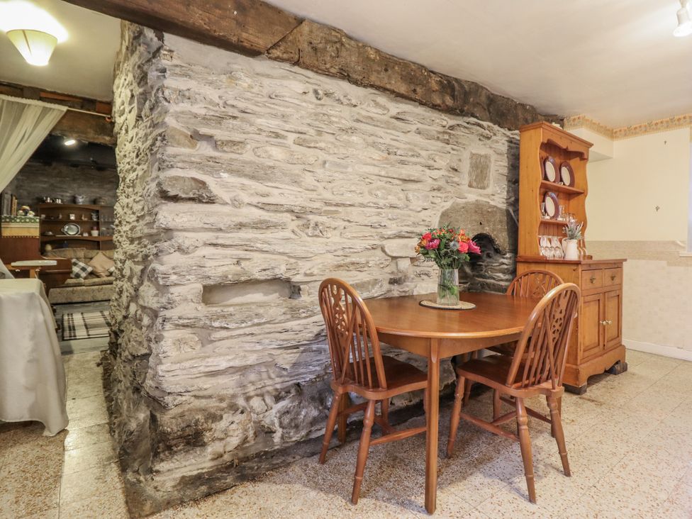 A dining room with a stone wall and table at Cynfal Fawr near Blaenau Ffestiniog