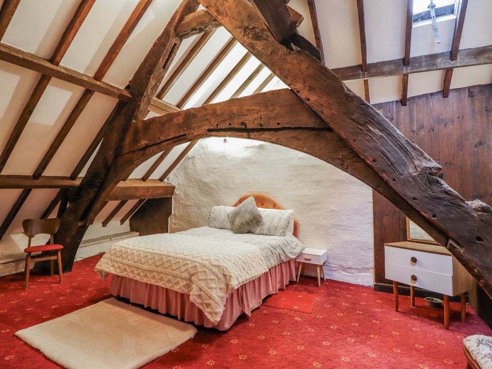 A bedroom with a bed, chair and wooden beams at Cynfal Fawr Near Blaenau Ffestiniog