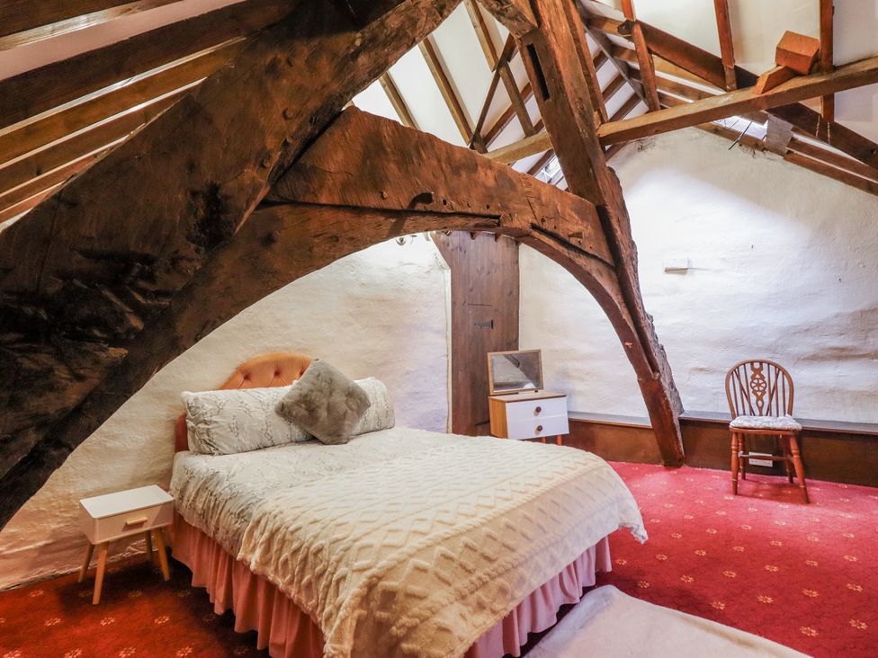 A bedroom with a bed, chair, and mirror at Cynfal Fawr Near Blaenau Ffestiniog