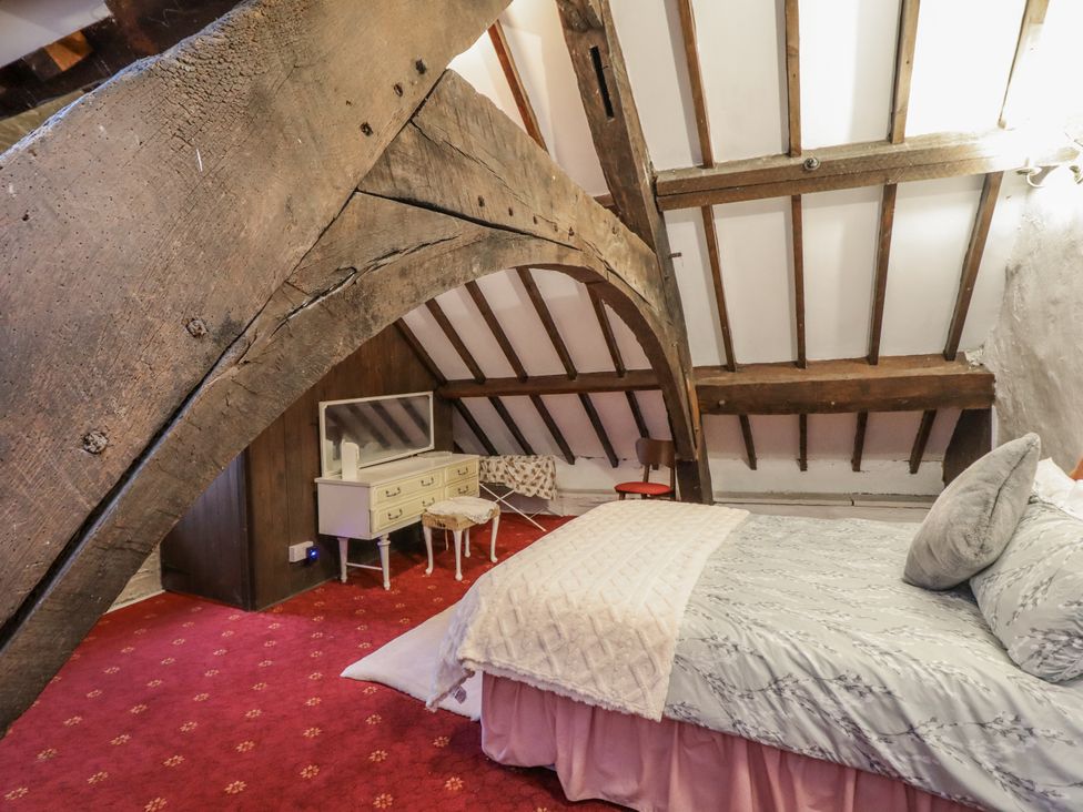 A bedroom with bed, dresser, and wooden beams at Cynfal Fawr Near Blaenau Ffestiniog