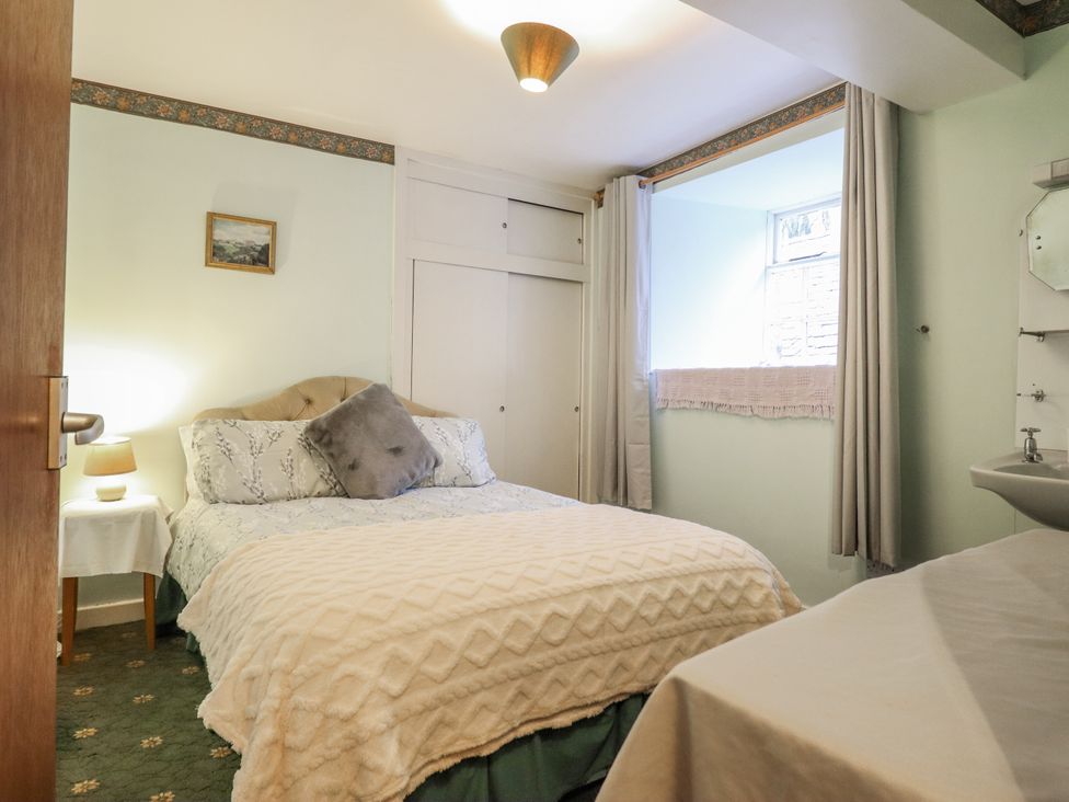 A bedroom with a bed, lamp, and window at Cynfal Fawr Near Blaenau Ffestiniog