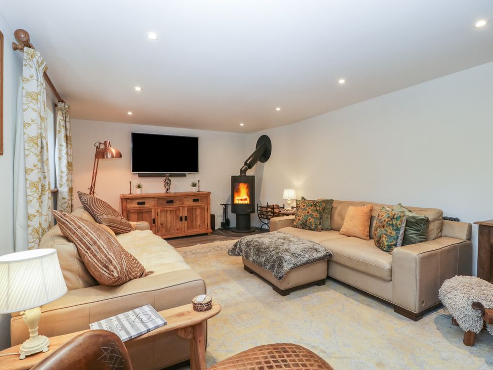 A living room with leather sofas and a wood burning stove at Graig Cottage in Cwmcarn