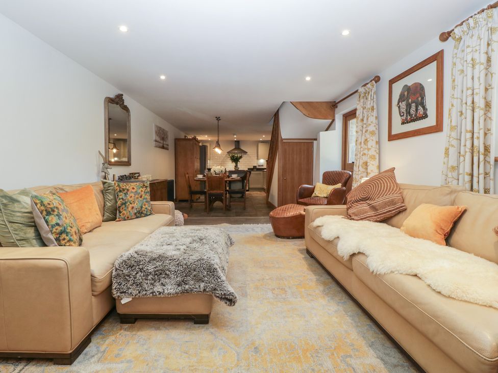 A living room with two beige sofas and a dining area in the background at Graig Cottage in Cwmcarn