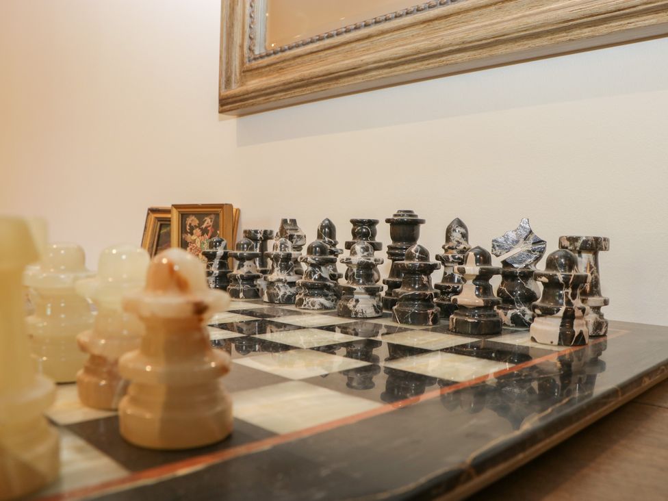 A chessboard with black and white marble chess pieces and framed pictures on a wall at Graig Cottage in Cwmcarn