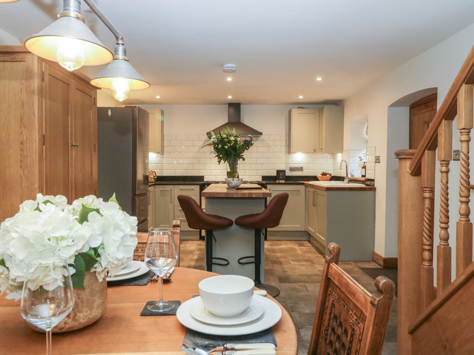 A kitchen and dining area with wooden furniture and cabinetry at Graig Cottage in Cwmcarn