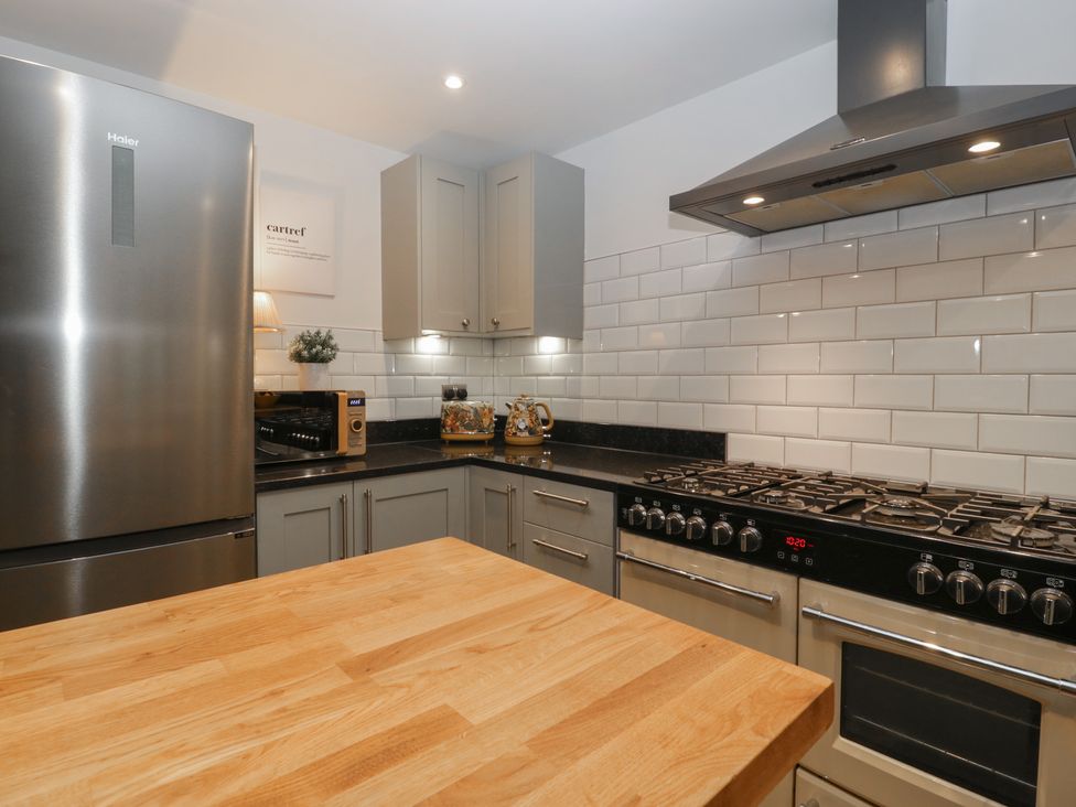 A kitchen with stainless steel refrigerator and stove wooden countertop and grey cabinets at Graig Cottage in Cwmcarn