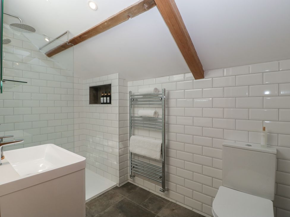 A bathroom with a shower area a towel rack a toilet and a sink at Graig Cottage in Cwmcarn