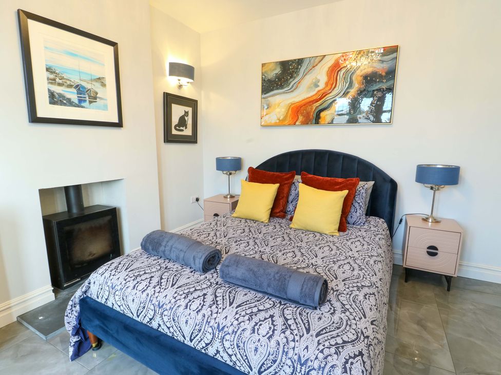 A bedroom featuring a bed, bedside tables, and artwork at Bronallt in Cemaes Bay