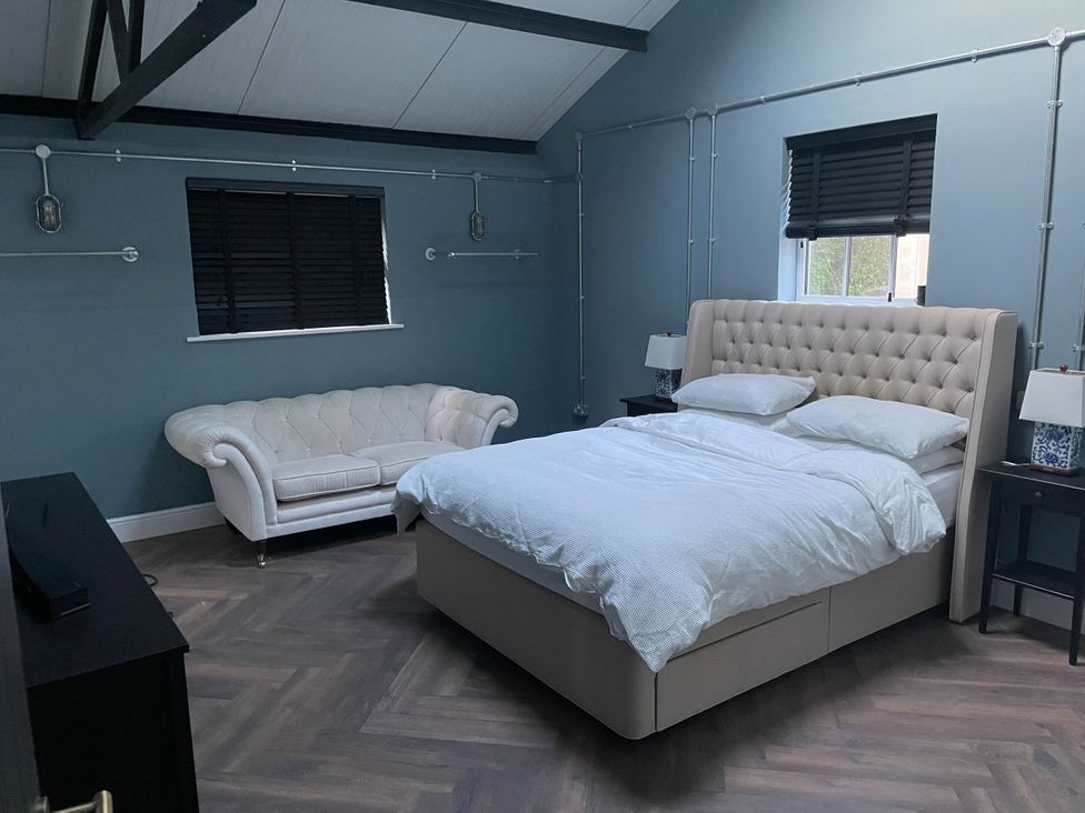 A bedroom with a bed, sofa, and lamp at The Old Workshop in Wormshill near Harrietsham