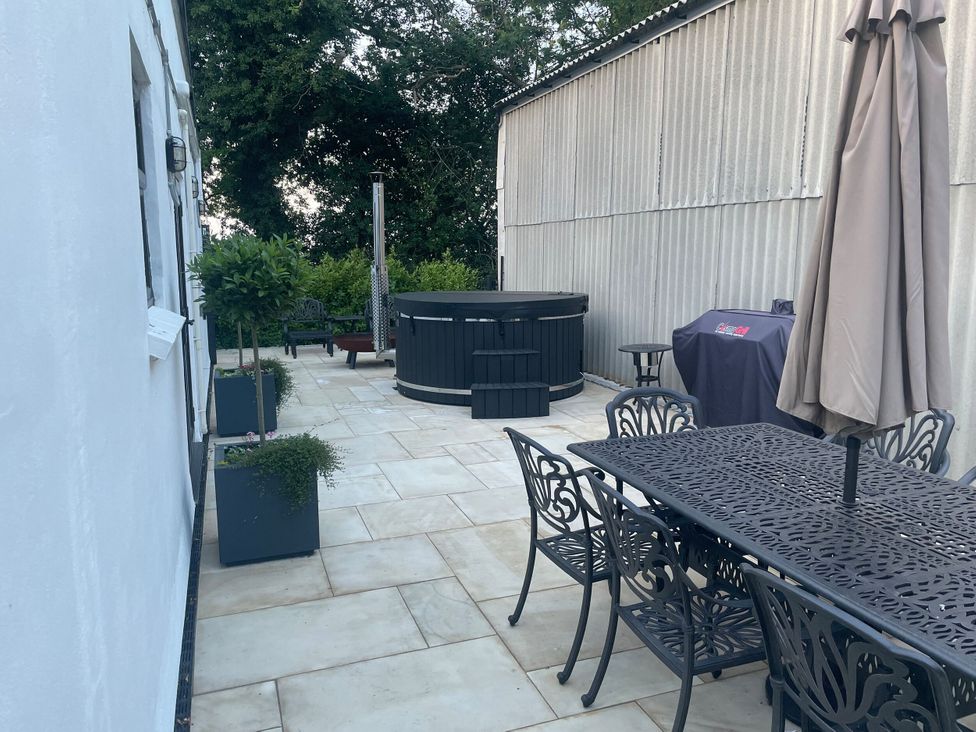 An outdoor area with a hot tub and dining set at The Old Workshop in Wormshill near Harrietsham