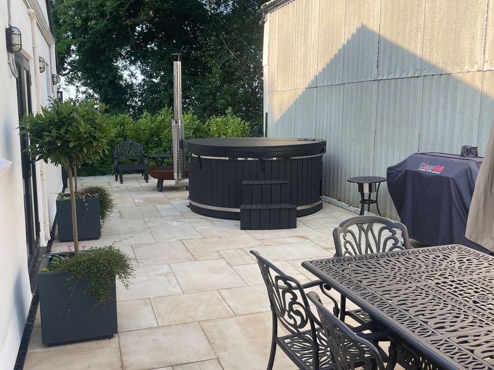 An outdoor patio with a hot tub and seating area at The Old Workshop in Wormshill near Harrietsham