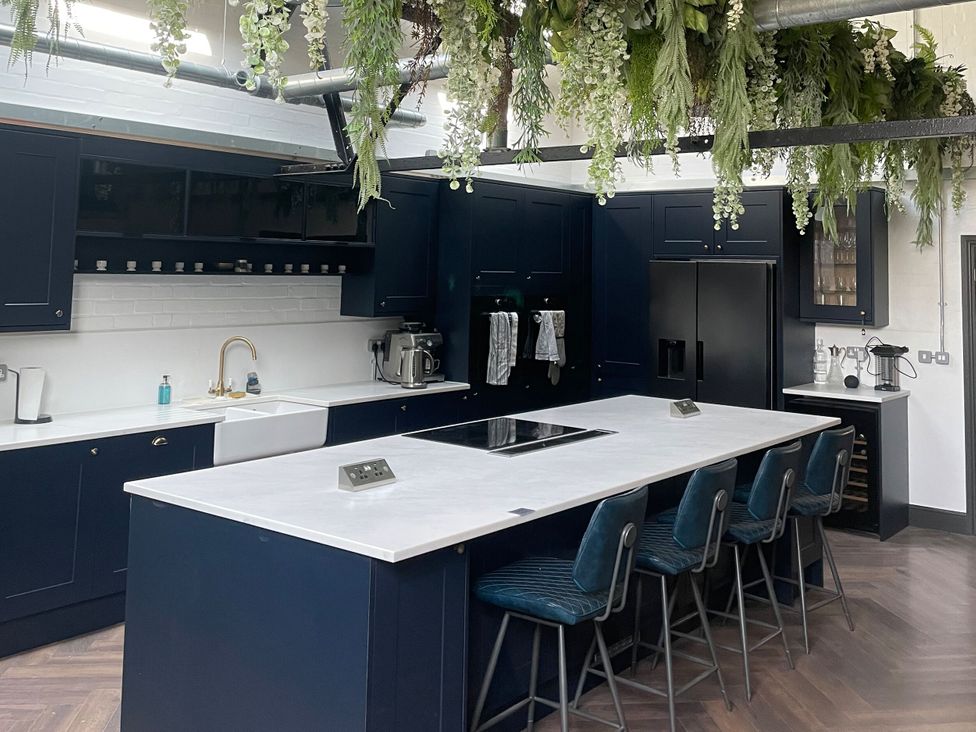 A kitchen with a large island and bar stools at The Old Workshop Wormshill near Harrietsham