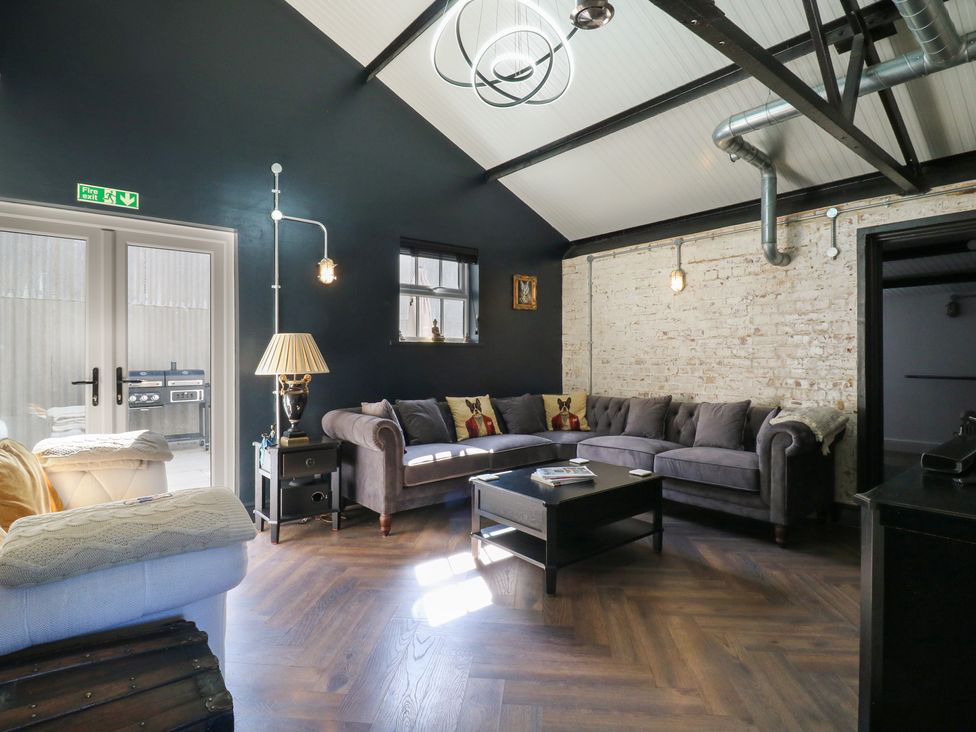 A living room with a sofa, table, and light fixtures at The Old Workshop in Wormshill near Harrietsham