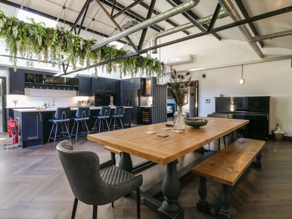 A dining room with a table and bar stools at The Old Workshop in Wormshill near Harrietsham
